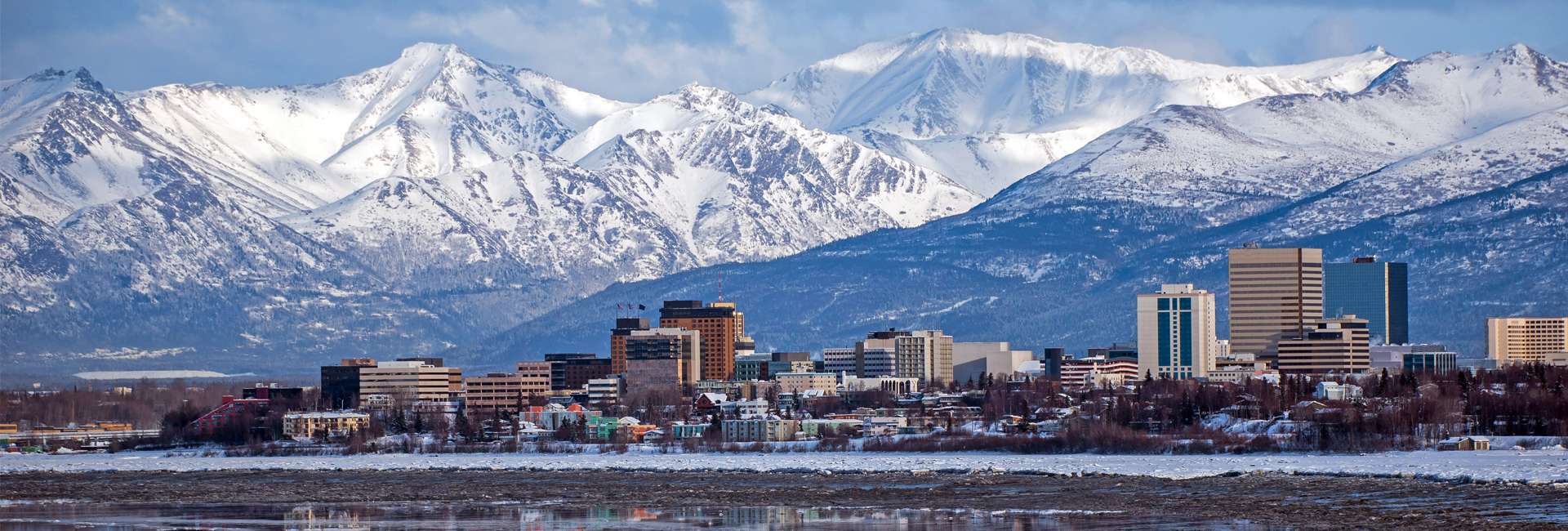 Anchorage, Alaska skyline with mountains in the background and reflection inwater