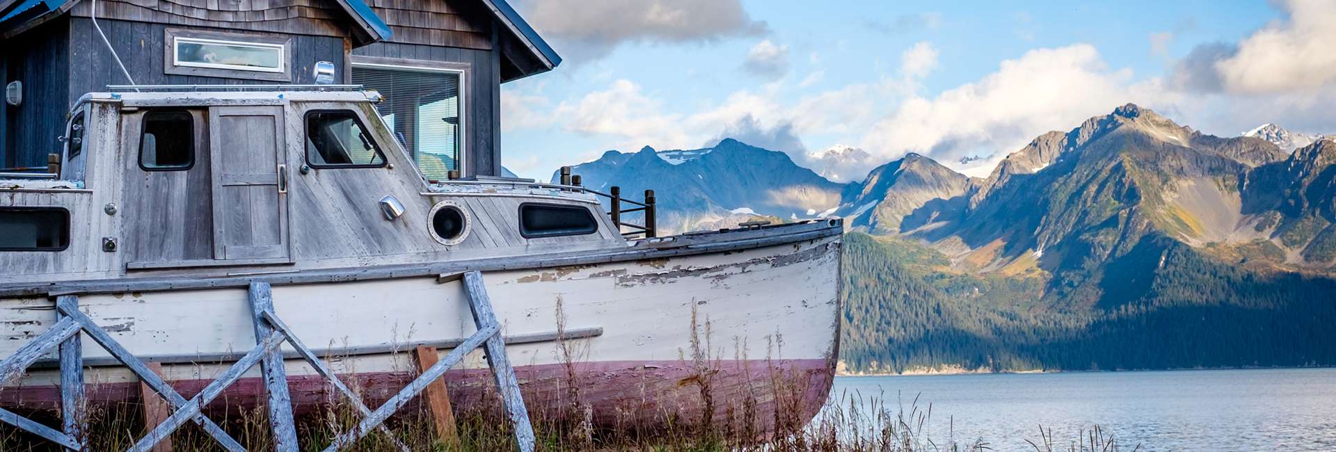 An old ship standing on the ocean shore in the bay of Kenai, Alaska, with a mountainbackground